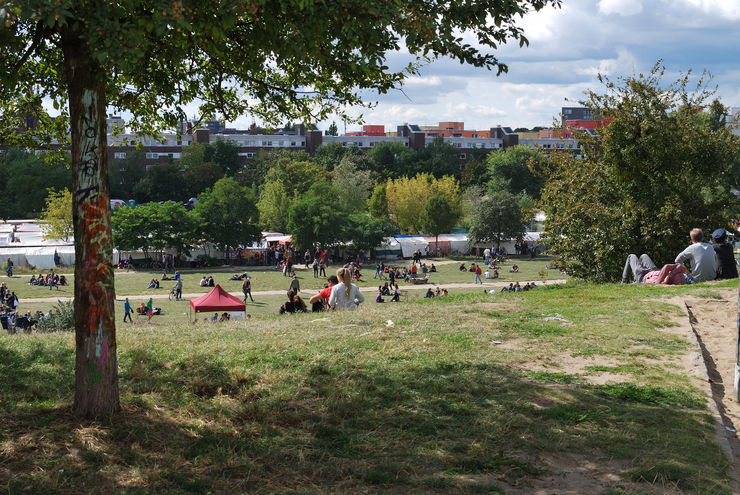 People relaxing in the grass above the Mauerpark Sunday flea market