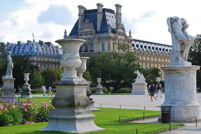 Statues and flowers backed by the Louvre Palace at Jardin des Tuileries