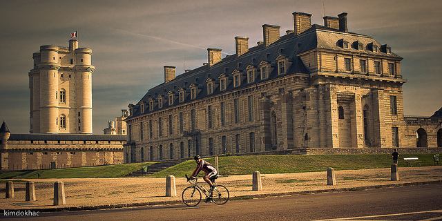 A lone cyclist riding past Château de Vincennes